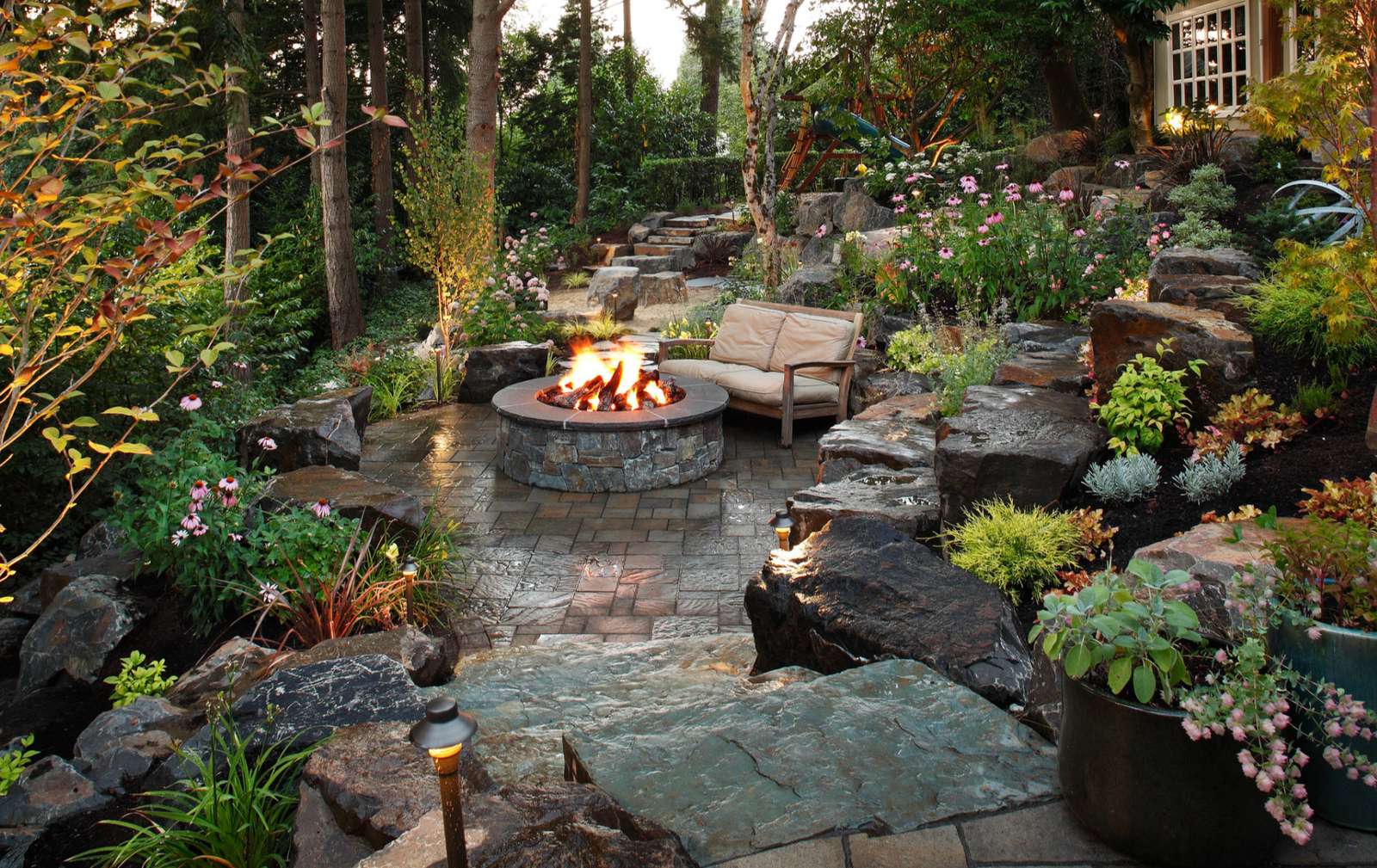 Stone fire pit surrounded by garden and boulders